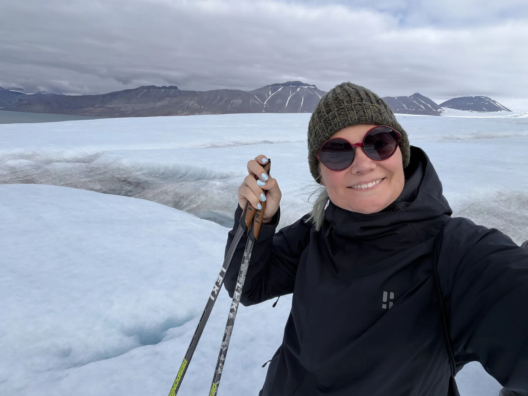 The author on the glacier surface, a moulin and mountains behind